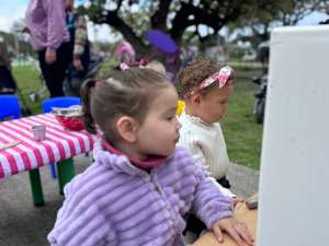 Dos niñas jugando en una cocinita al aire libre en el festejo del Día del Bebé